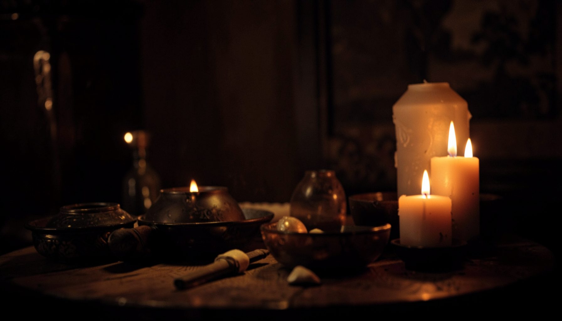 Warm candlelight tones and deep shadows in an intimate interior scene with ritual objects